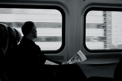 火车里的人拿着报纸看窗户灰阶摄影